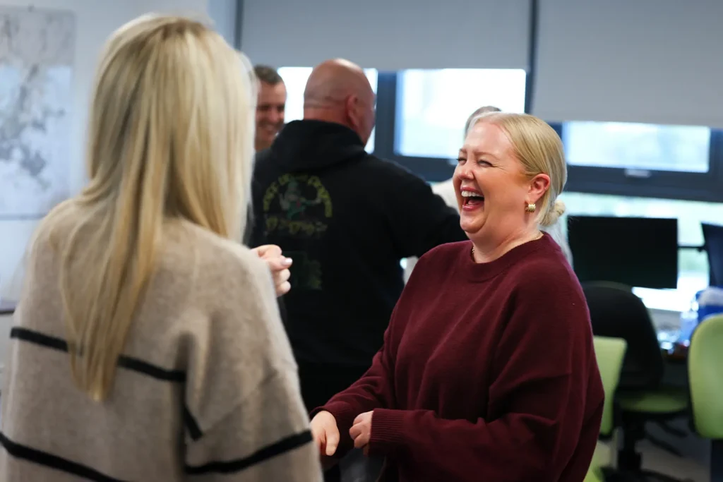 Woman laughing and talking with colleagues in an office setting