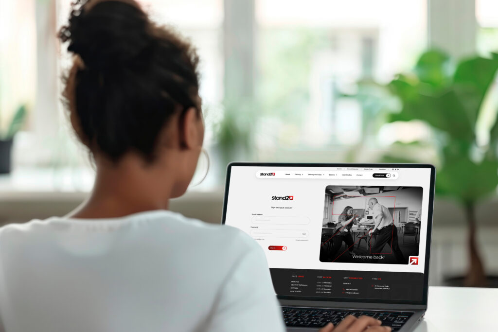 Person viewed from behind using a laptop displaying the Stand25 website login page