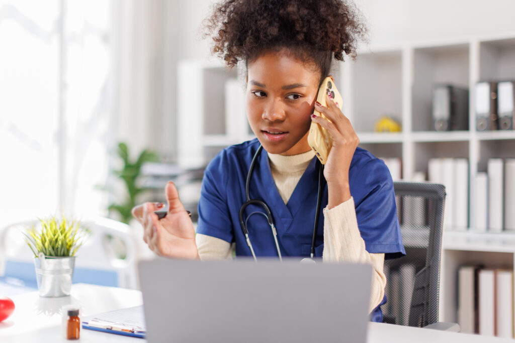 Young doctor on the phone sat behind a laptop
