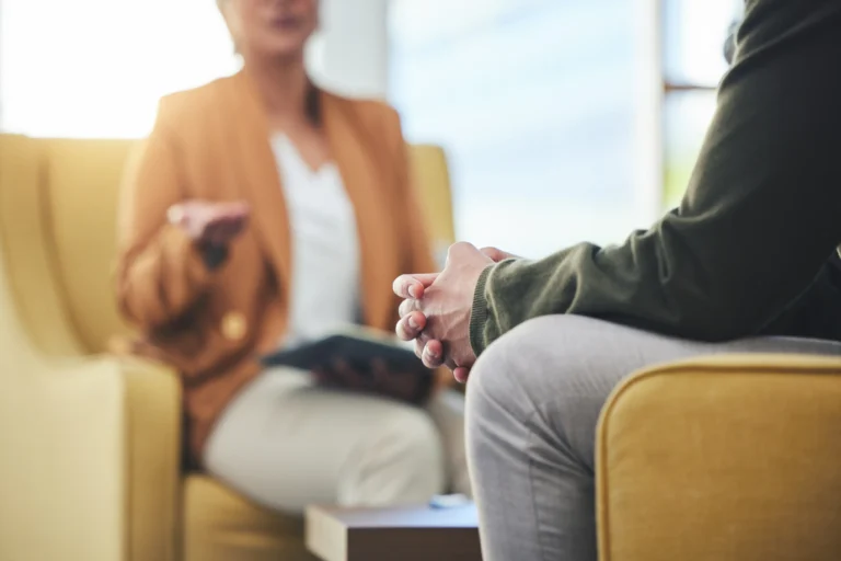 Man sat on a chair with hands clasped
