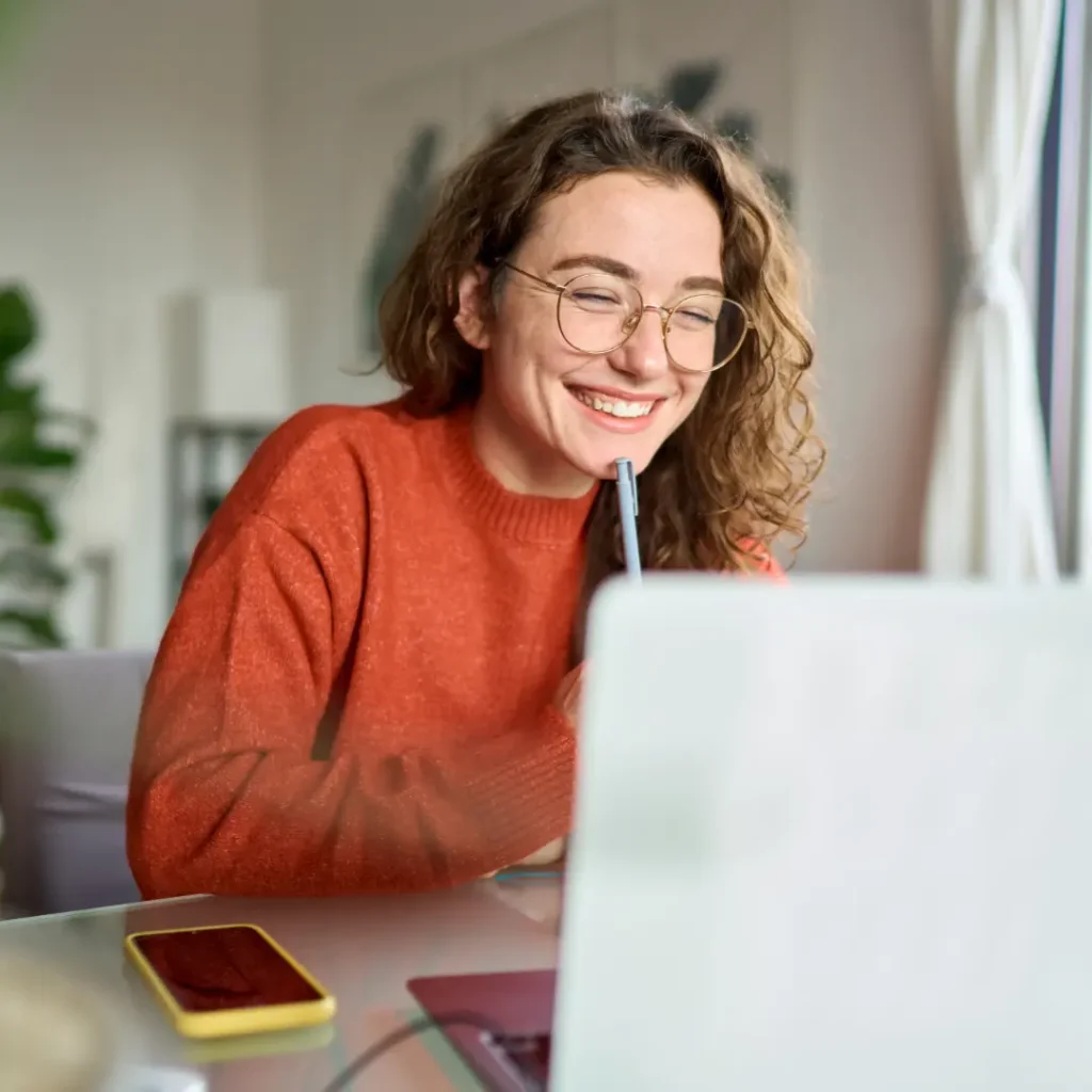 Woman laughing sat in front of a laptop