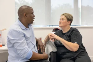 Two people engaged in a focused conversation while seated across from each other in an office or clinic setting