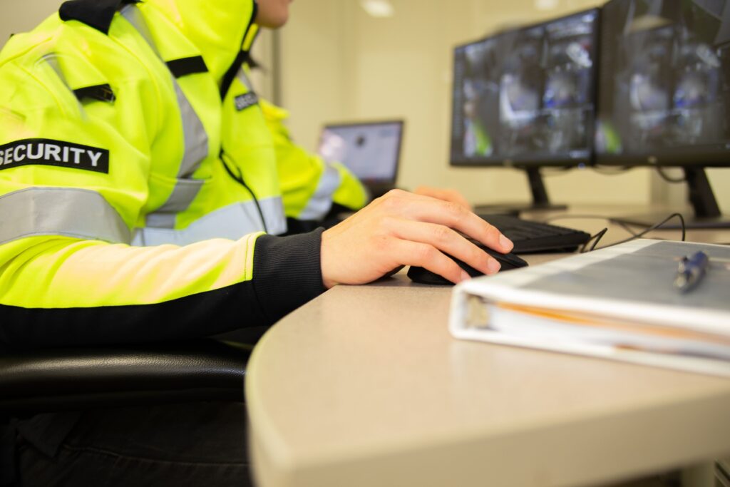 A security team watching over CCTV surveillance monitors with green screen.