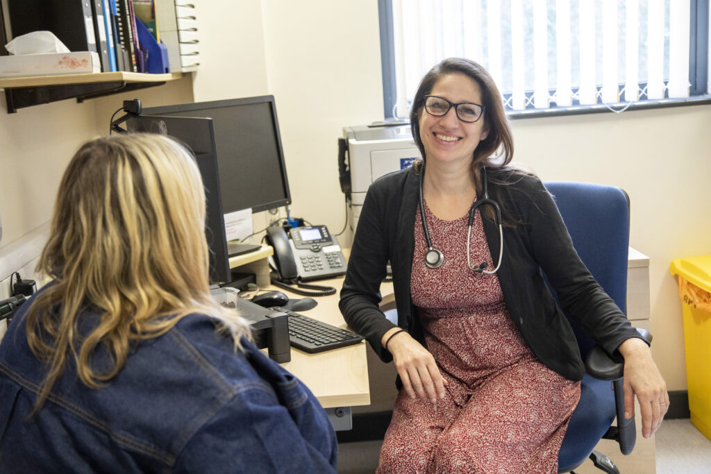 Doctor in glasses smiling with patient in medical practice