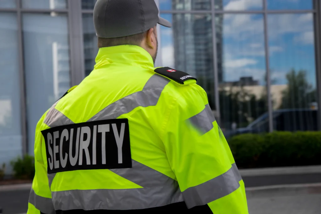A lone security guard stands watch outside the building he is protecting