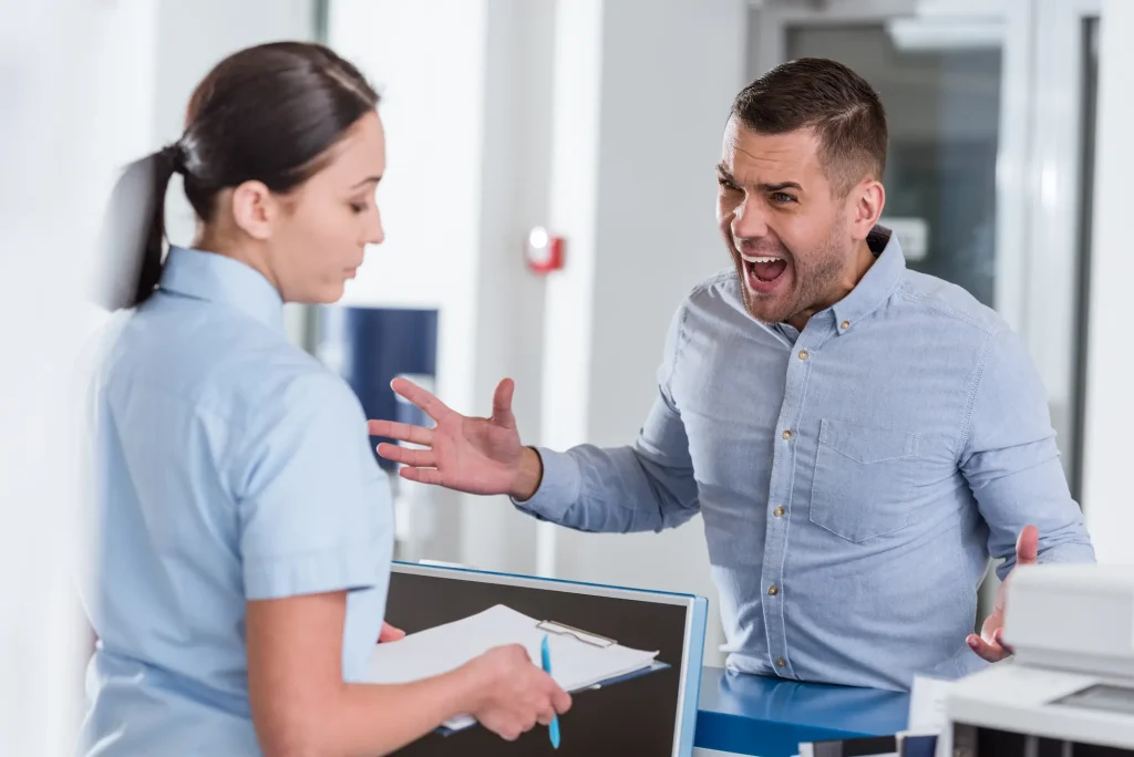 An aggressive male patient shouts at a receptionist