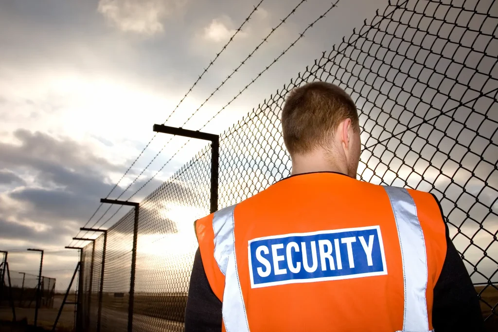 A lone security guard patrols the perimeter of an area he is guarding