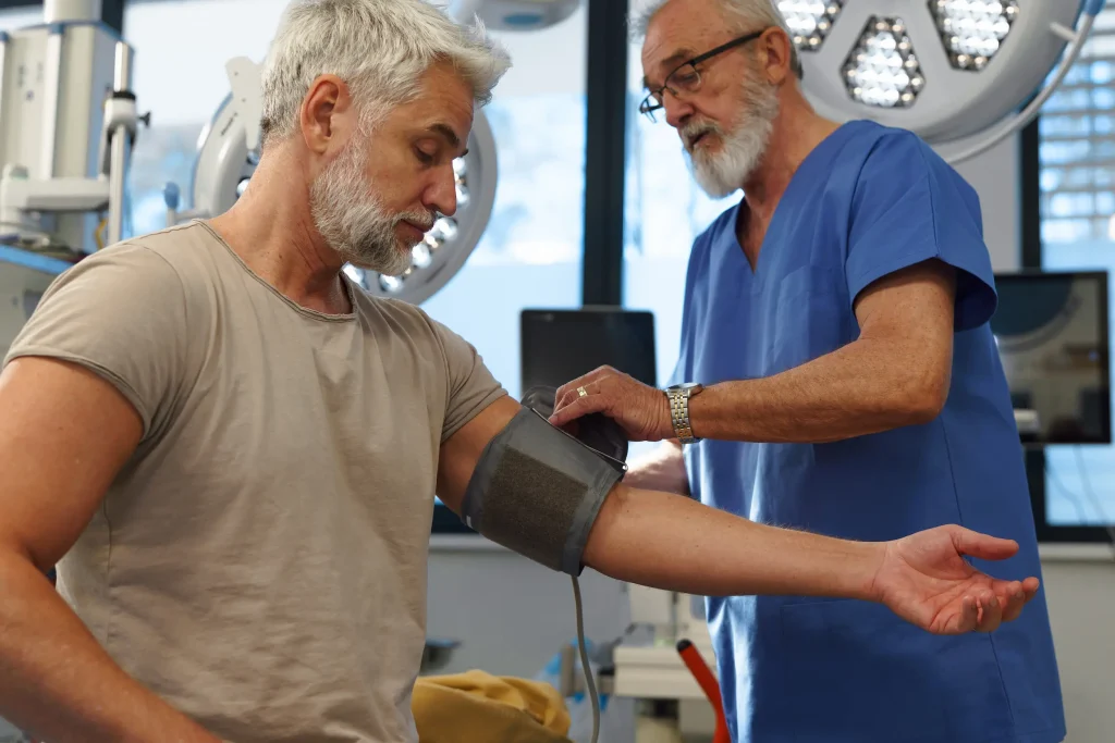 A male nurse takes a patients blood pressure in hospital