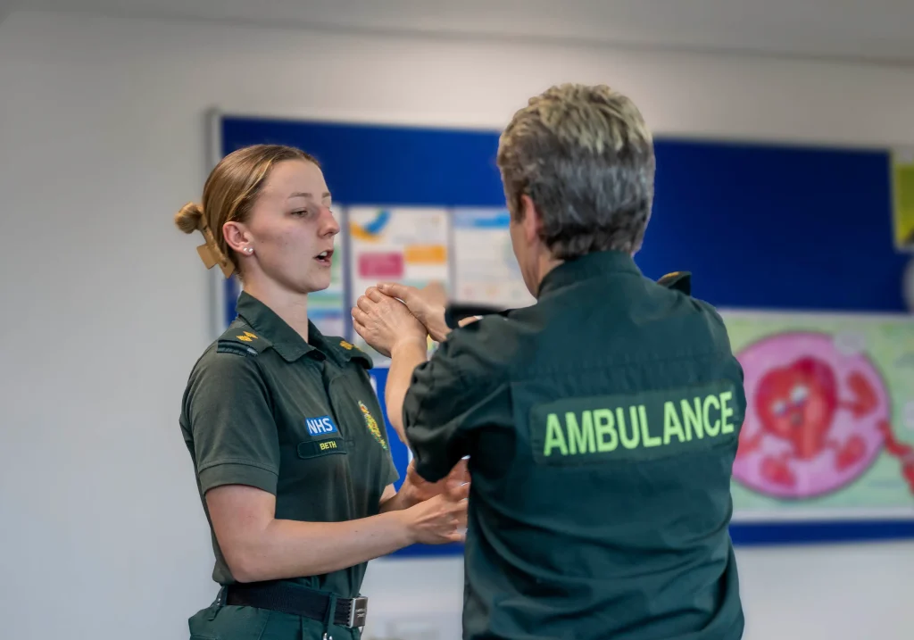 A paramedic learns how to deal with a throat grab during her conflict resolution training session delivered by Stand2