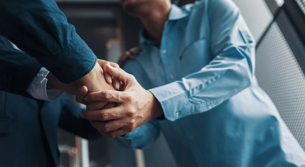 Two people shaking hands, representing Stand2's ongoing training partnership with probation services across England