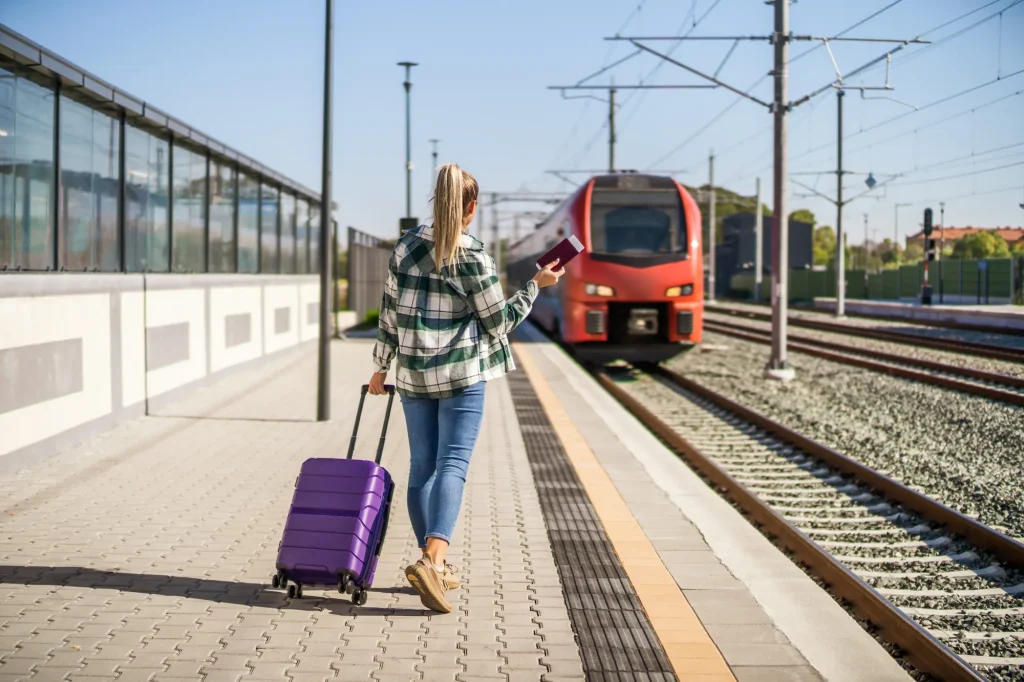 A woman with a suitcase and a train ticket on a train platform